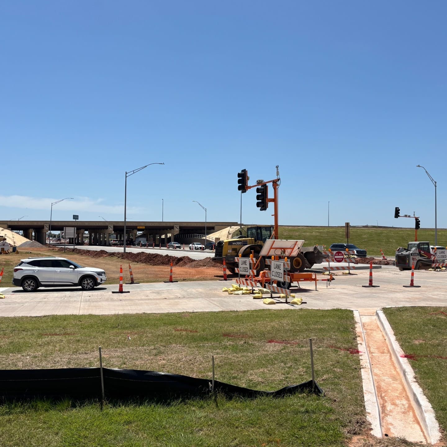 Construction under way on Garth Brooks Boulevard, with newly poured concrete lanes, traffic signals and equipment beside the I-40 overpass
